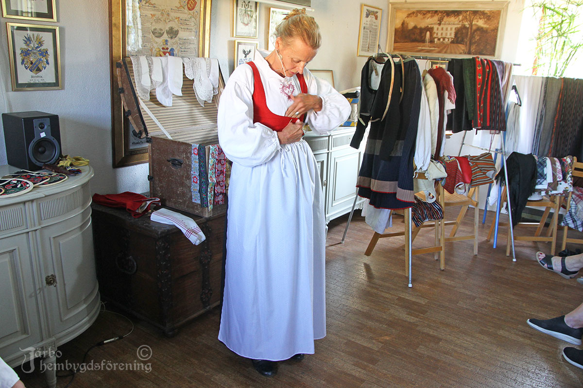 Nu är det dags för det röda fläbblivstycket för högsta helg att komma på. Eftersom det är sommar syns ärmarna i vitt på överdelen, på vintern hade alla en svart tröja under det röda livet.