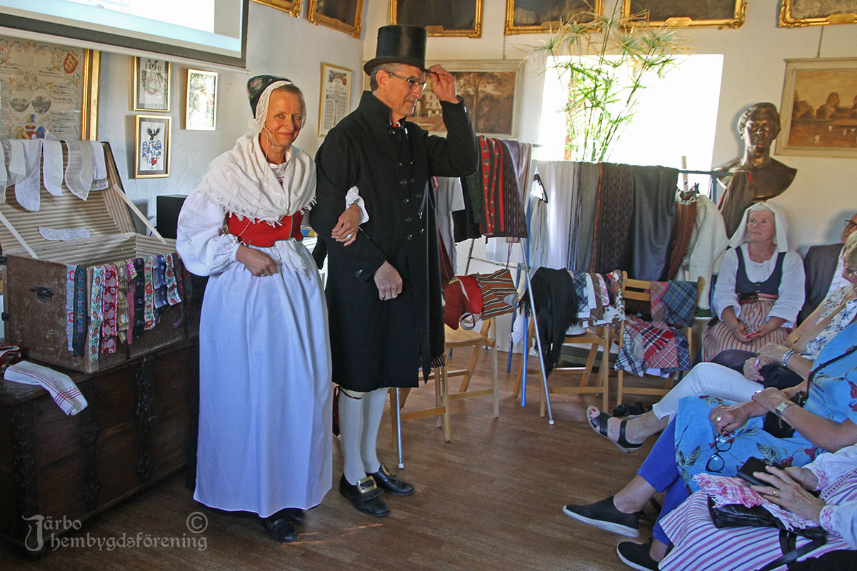 Par från Ovansjö klädda för högsta helg på väg till kyrkan. Stilig herre i svart rock och hög svart hatt.