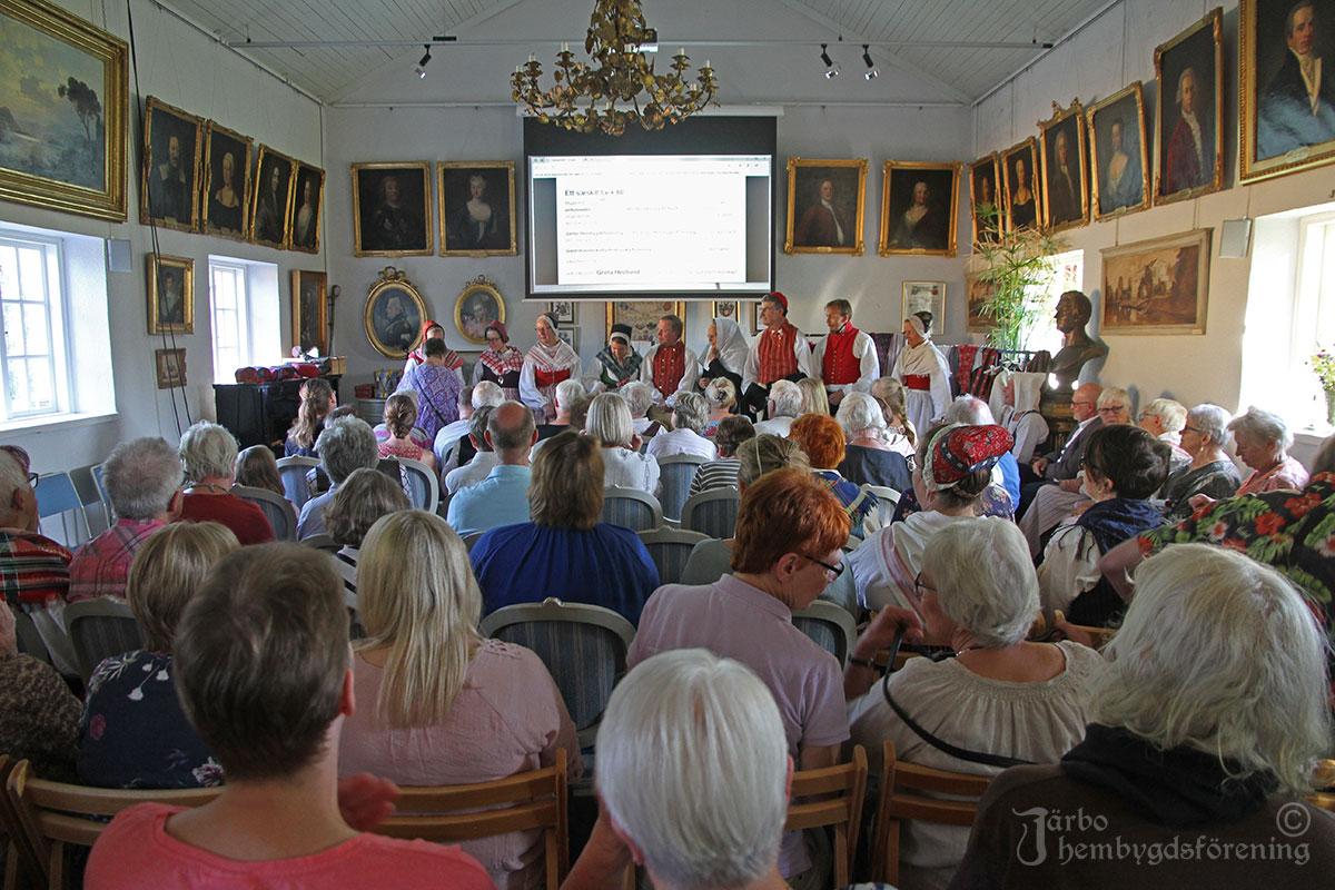 IMG_1839 Glada åhörare i Stenhuset i Gästrike-Hammarby beundrar de olika varianterna av dräkter från Ovansjö som visades under kvällen. Många av besökarna var också klädda i dräkt.