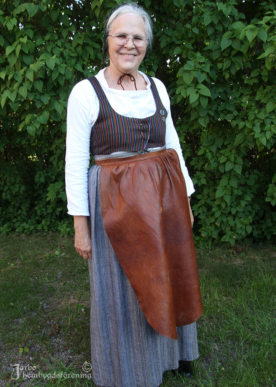 IMG_1902 Elisabeth Lindholm har på sig en vardagsdräkt från Ovansjö med randig livkjol och en enkel vit särk. Hemvävt blårandigt förkläde i linne och ovanpå det ett till i skinn. Hon ska jobba hårt hon! Hylka på huvudet.