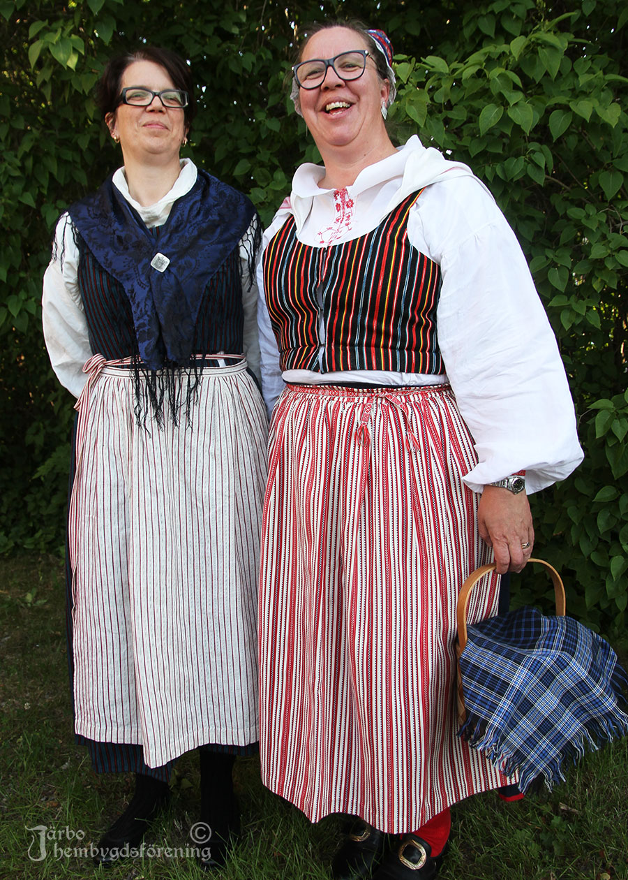 IMG_1916 Ulrika har en dräkt från Arbrå, Hälsingland. Susanne Adman har en äldre variant av Ovansjödräkt med hemvävt randigt skunklivstycke och mörkblått tvinnskört, det vill säga en tätt veckad kjol med anor från vikingatiden, som använts i Ovansjö. Rödrandigt kvistförkläde och skarpmössa med stycke till.