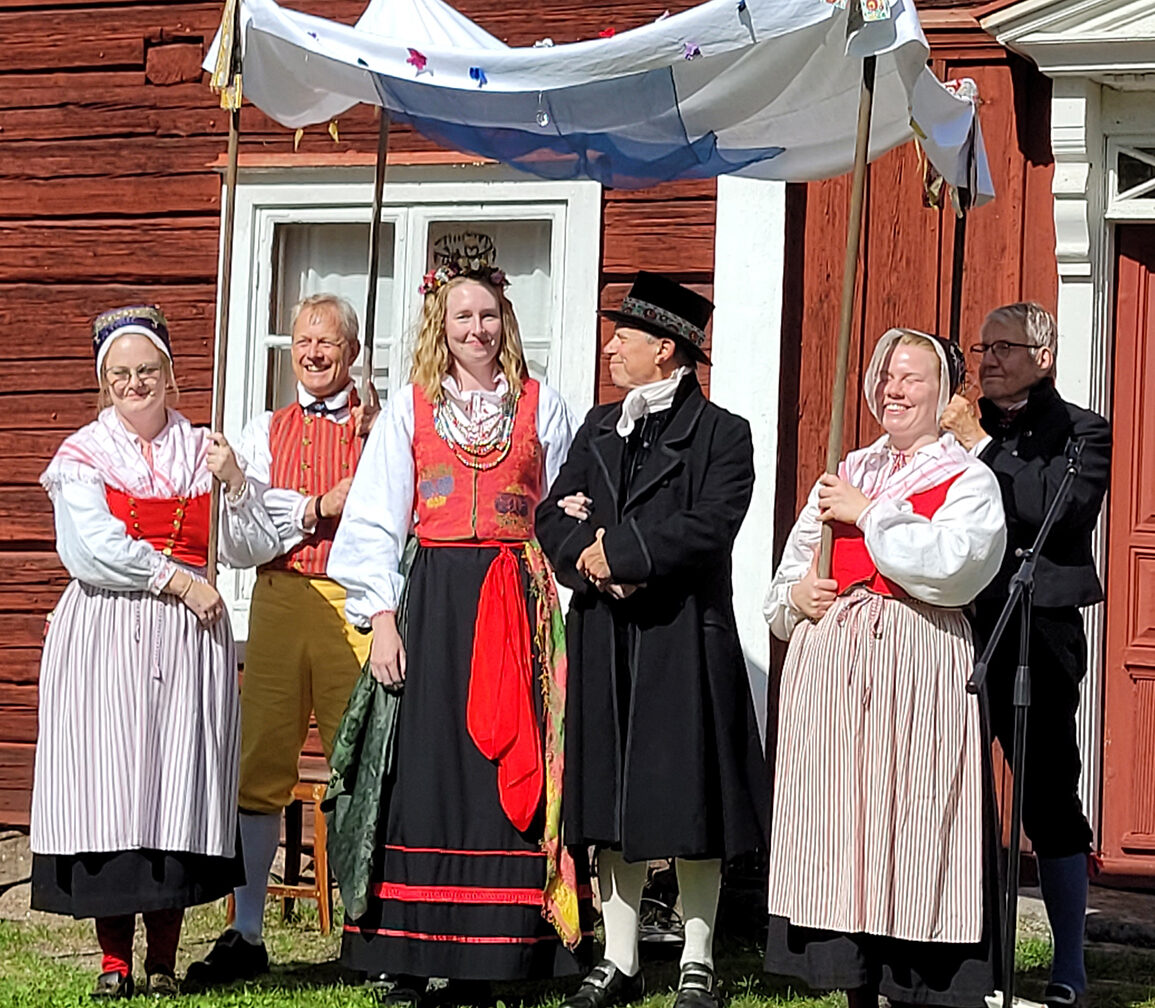 Brudparet står uppställda under brudpällen för att beundras av alla bröllopsgäster. Brudpällen hålls uppe av fyra personer, Jonas har på sig Ovansjödräkt och Olle har bergsmansklädnad. Kvinnorna har på sig den dräkt som togs blev vanlig under 1900-talet, men ursprungligen användes andra dagen efter bröllopet.